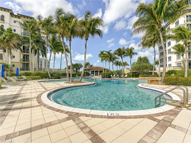 Private community pool featuring sundeck with umbrellas
