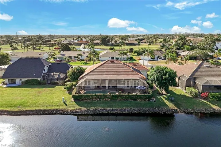 Aerial view showcasing the home’s position along the lake with surrounding neighborhood and green space. Highly desirable location within the community!