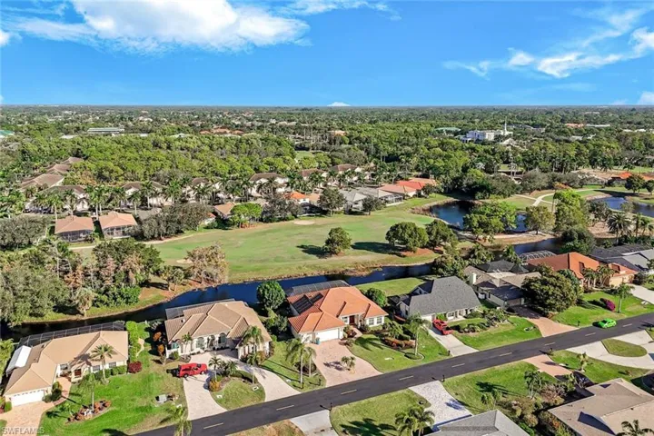 Wide aerial view highlighting nearby golf courses, lakes, and the surrounding residential community. Spanish wells is beautifully manicured with the golf course and tropical plants and vegetation.