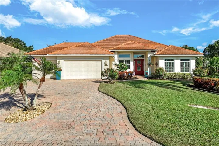 Front elevation of the home featuring a paver driveway, mature landscaping, and a welcoming entry. Updated landscaping add the perfect touch to this home.