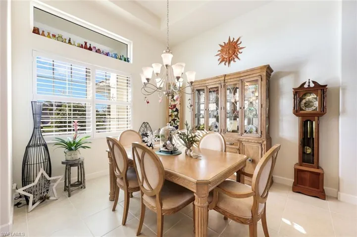 Formal dining room featuring tray ceiling detail, custom lighting, and large windows with plantation shutters. Enjoy many family evenings around the dining room table sharing laughs and memories.