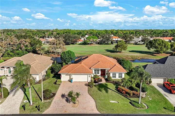 Spacious paver driveway leading to the attached garage, framed by tropical landscaping. The oversize driveway make it a breeze coming and leaving!