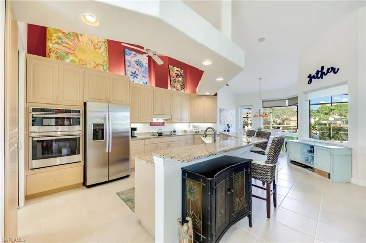 Spacious kitchen with stainless steel appliances, oversized island seating, and an open view to the dining area.