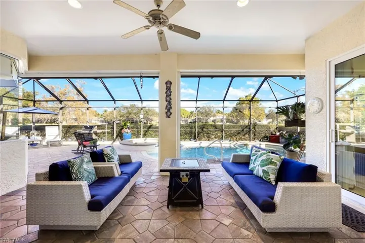 Covered outdoor living area with tiled flooring, ceiling fan, and views overlooking the screened pool enclosure. Does it get much better than relaxing poolside here?