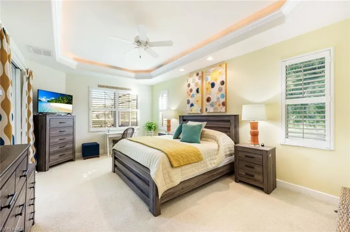 Primary bedroom with tray ceiling detail, private access to the lanai, and ample space for bedroom furnishings. Easy and convenient access to the lanai and pool.