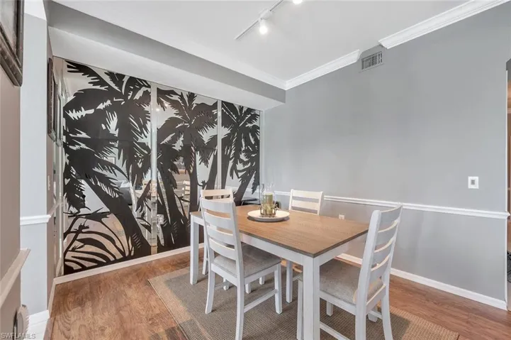 Dining room with wood finished floors, rail lighting, baseboards, and ornamental molding