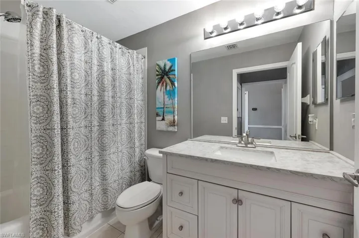 Bathroom with toilet, vanity, and shower / bathtub combination with curtain