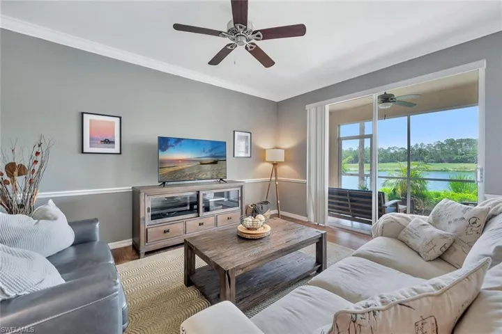 Living room with baseboards, a ceiling fan, wood finished floors, and crown molding