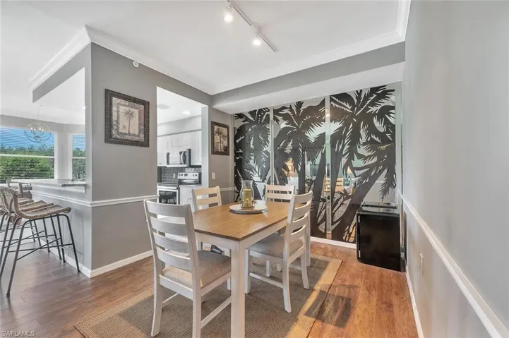 Dining space with wood finished floors, track lighting, a chandelier, and crown molding