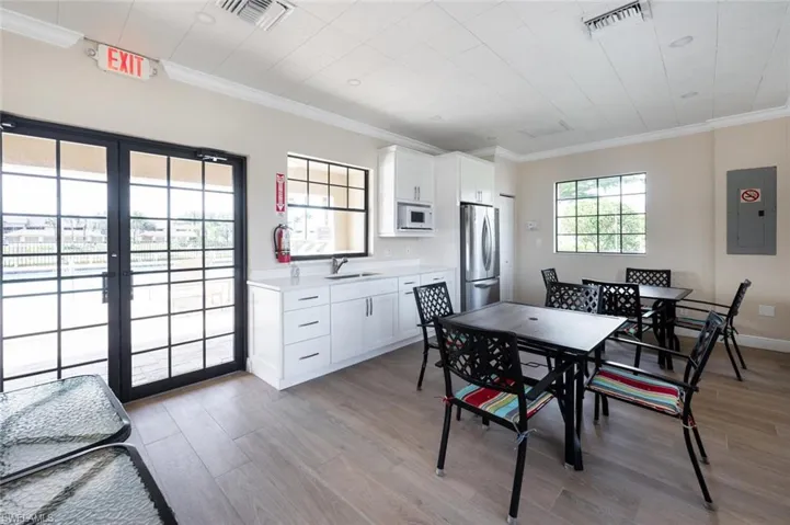 Dining area with electric panel, light wood-type flooring, crown molding, french doors, and baseboards