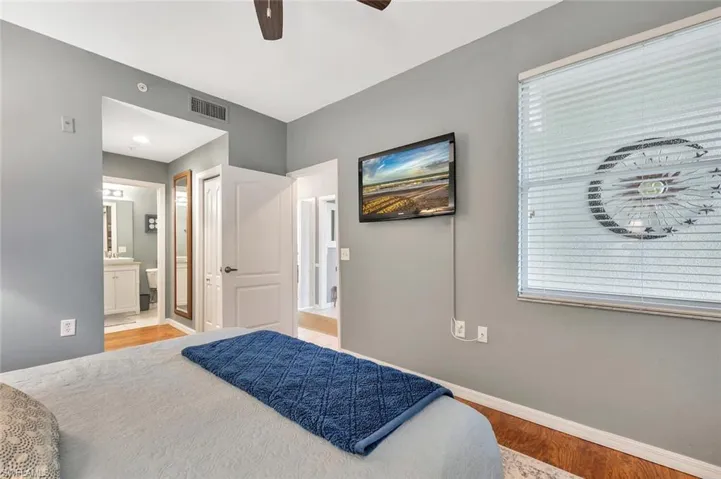 Bedroom with wood finished floors, baseboards, connected bathroom, and ceiling fan