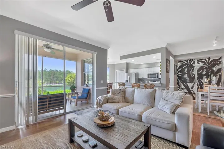 Living room with ceiling fan, baseboards, light wood-style flooring, and ornamental molding