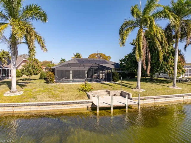 Dock area with a lanai, a water view, a yard, and a sunroom