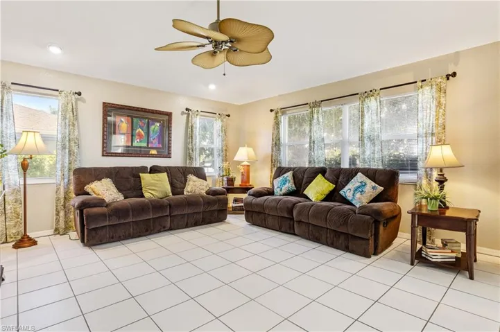 Living area with ceiling fan, light tile patterned floors, and healthy amount of natural light