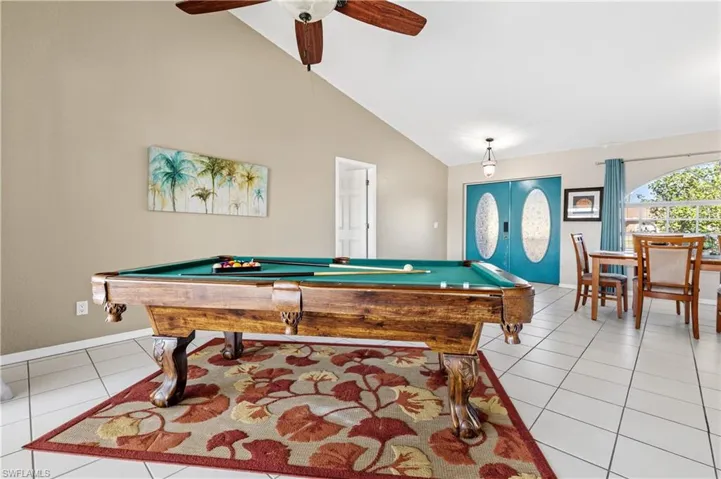 Game room with billiards table, vaulted ceiling, a ceiling fan, and light tile patterned floors
