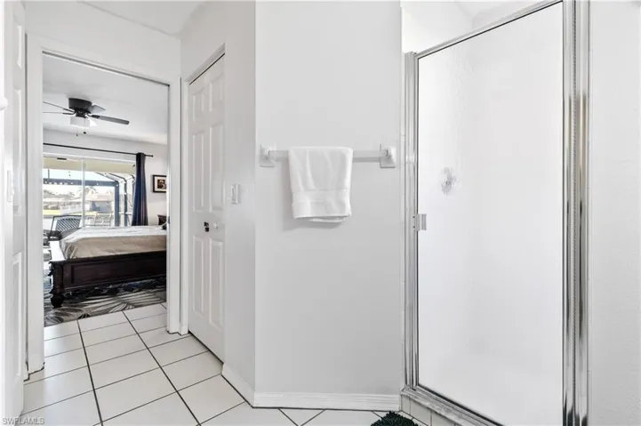 Ensuite bathroom with light tile patterned floors, a stall shower, and a ceiling fan