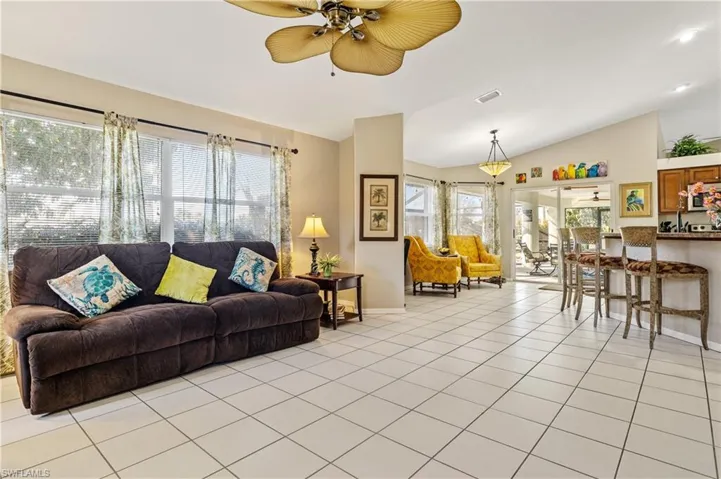 Living room with ceiling fan, light tile patterned floors, and lofted ceiling