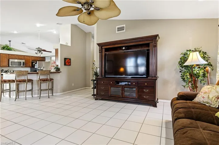 Living area with lofted ceiling, a ceiling fan, and light tile patterned floors