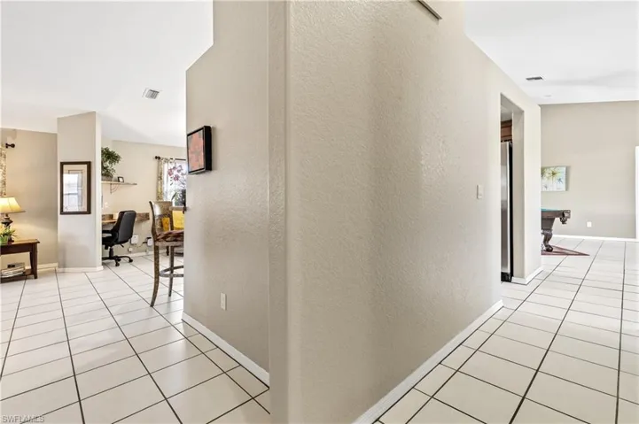 Corridor featuring a desk, a textured wall, and light tile patterned floors
