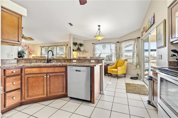 Kitchen with wood finish cabinetry, a ceiling fan, stainless steel appliances, and pendant lighting