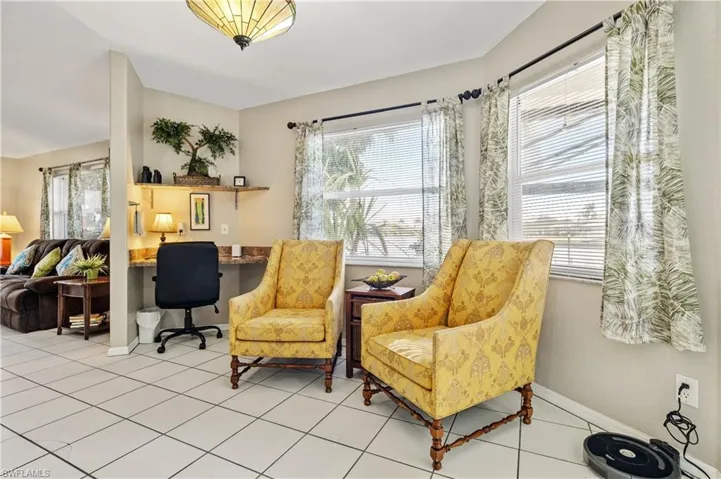 Sitting room with light tile patterned floors and a desk