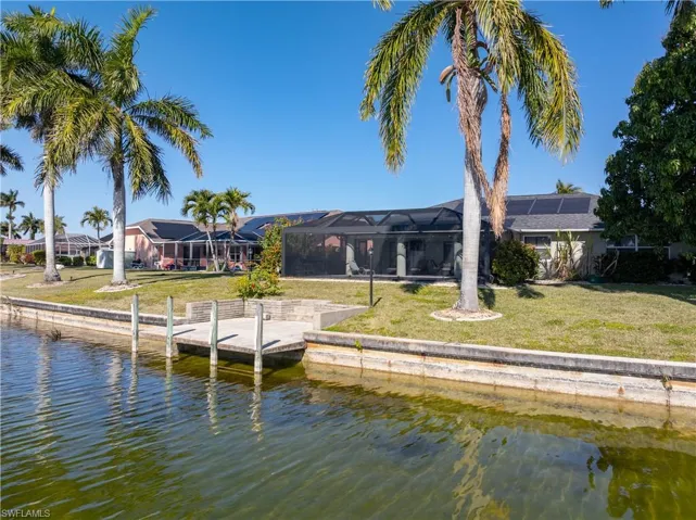 Rear view of house with glass enclosure, a yard, a water view, and a sunroom