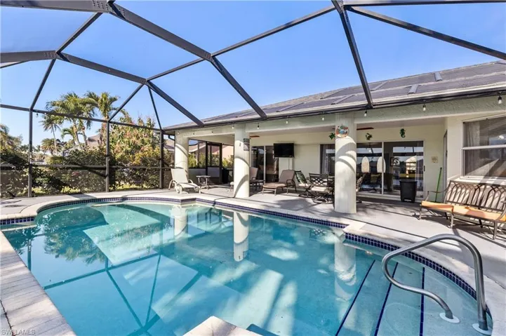 Outdoor pool with glass enclosure, a sunroom, and a patio