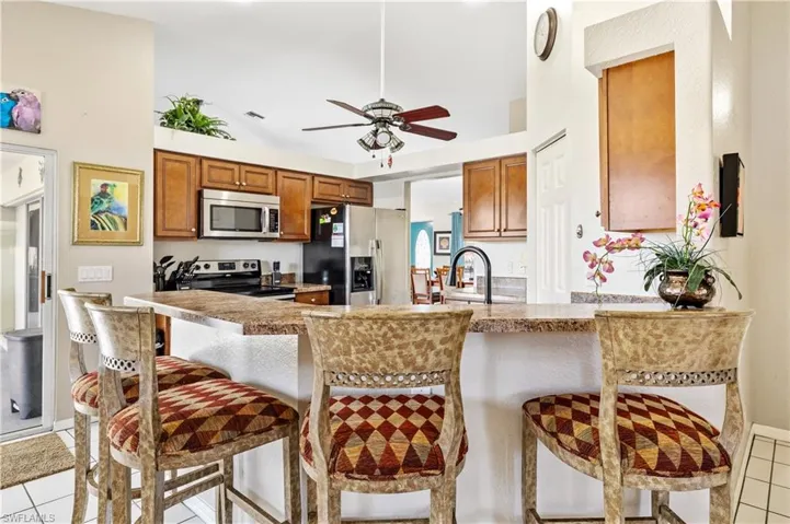 Kitchen with light tile patterned flooring, a breakfast bar area, wood finish cabinetry, and vaulted ceiling