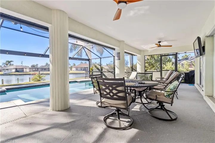 Sunroom / solarium featuring outdoor dining space, a ceiling fan, a patio, and a water view
