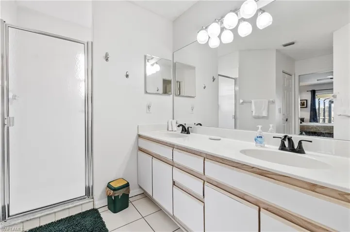 Ensuite bathroom with double vanity, a stall shower, and light tile patterned flooring