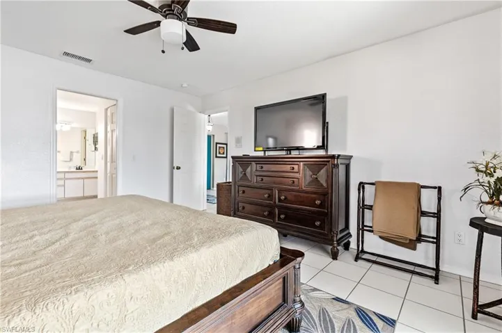 Bedroom with a ceiling fan, light tile patterned floors, and connected bathroom