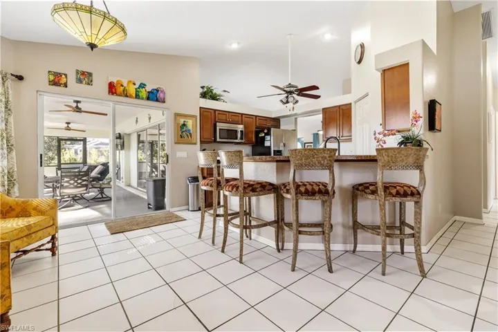 Kitchen with a breakfast bar, ceiling fan, wood finish cabinets, stainless steel appliances, and vaulted ceiling