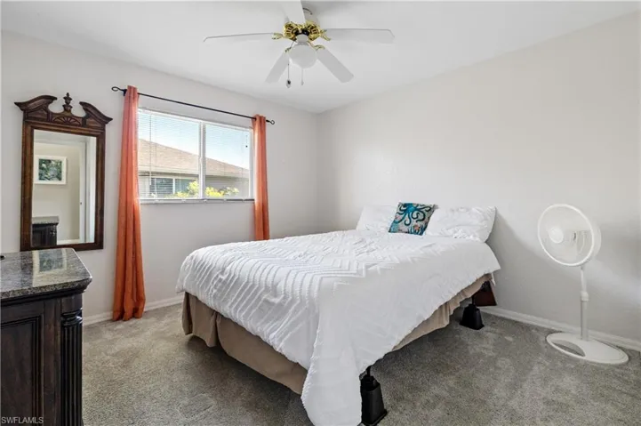 Carpeted bedroom with ceiling fan and baseboards