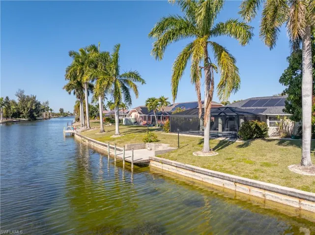 Dock area with a lawn, a sunroom, a water view, and glass enclosure