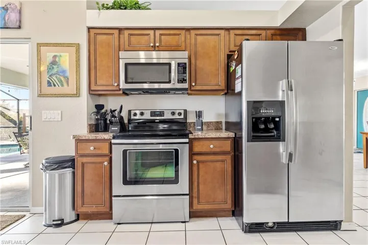 Kitchen with wood finish cabinetry, stainless steel appliances, and light tile patterned floors
