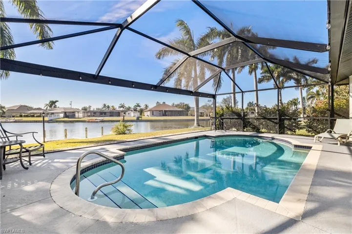 Outdoor pool with glass enclosure, a sunroom, a water view, a residential view, and a patio