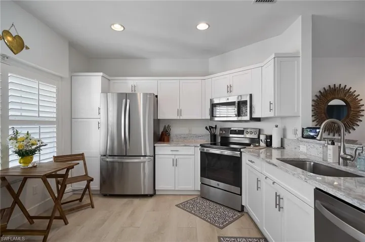 Kitchen featuring stainless steel appliances, sink, and white cabinets