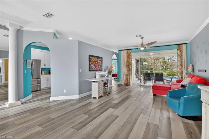 Living room with crown molding, decorative columns, light wood-style floors, ceiling fan, and recessed lighting
