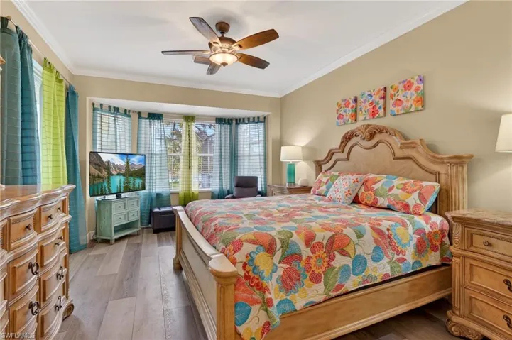 Bedroom featuring wood finished floors, ornamental molding, and a ceiling fan