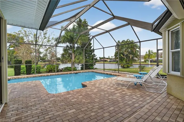 Outdoor pool with a patio area, a lanai, a water view, and a sunroom