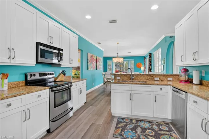 Kitchen with stainless steel appliances, white cabinets, recessed lighting, and crown molding