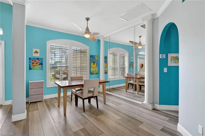 Dining area featuring ornamental molding, light wood finished floors, ceiling fan, and ornate columns