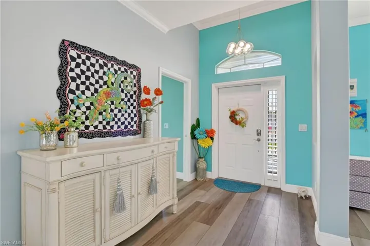 Entryway featuring laminate flooring, crown molding, and a chandelier