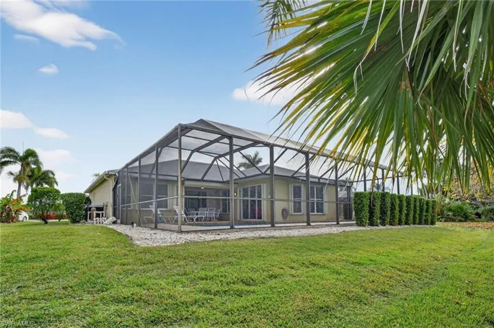 Rear view of property featuring a sunroom, glass enclosure, a yard, and an outdoor pool