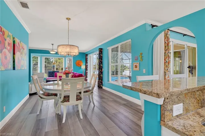 Dining room with wood finished floors, a chandelier, and crown molding