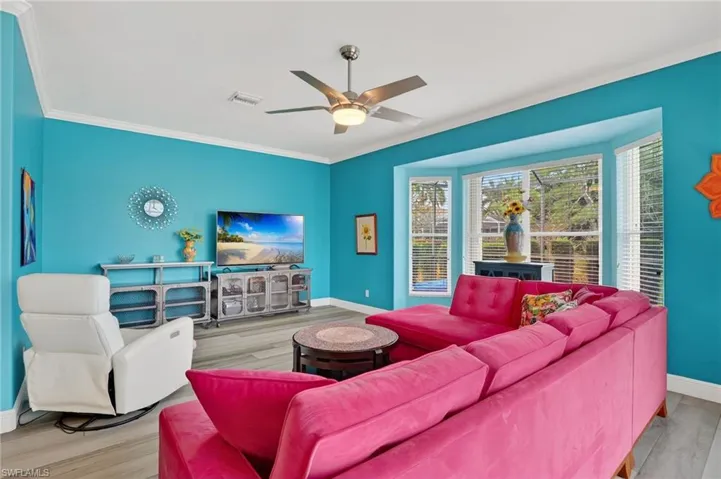 Living area with wood finished floors, a ceiling fan, and ornamental molding