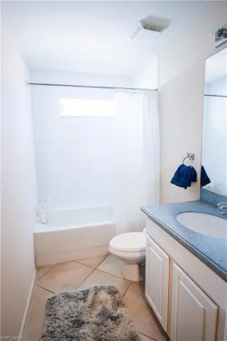 Full bathroom with shower / tub combo, vanity, toilet, and tile patterned flooring