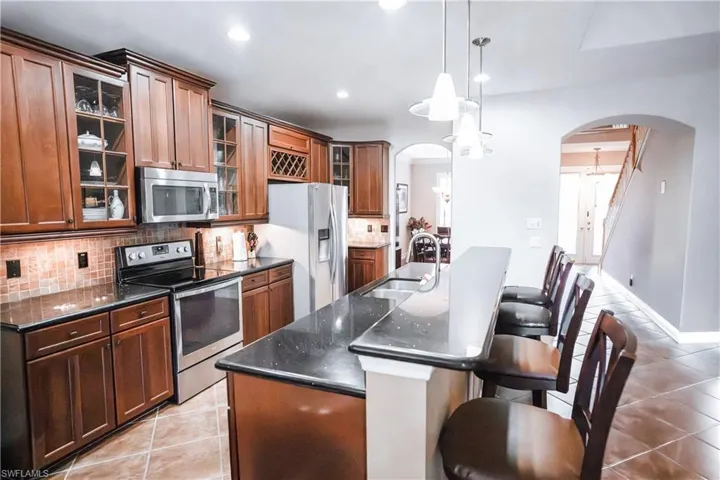 Kitchen featuring pendant lighting, an island with sink, stainless steel appliances, and sink