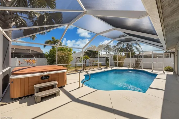 View of swimming pool with patio surround, a hot tub, and a fenced backyard