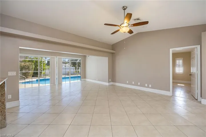 Living room with ceiling fan, light tile patterned flooring, and vaulted ceiling